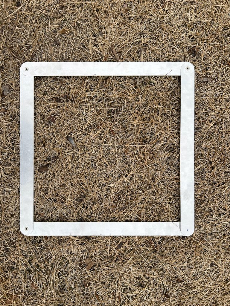 Metal square frame placed on dry grass