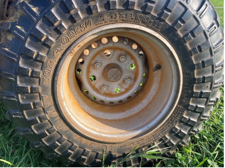 Close-up of a rugged tire with deep treads and orange dust in the wheel well.